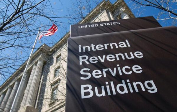 Low-angle view of the Internal Revenue Service (IRS) headquarters building sign with the American flag