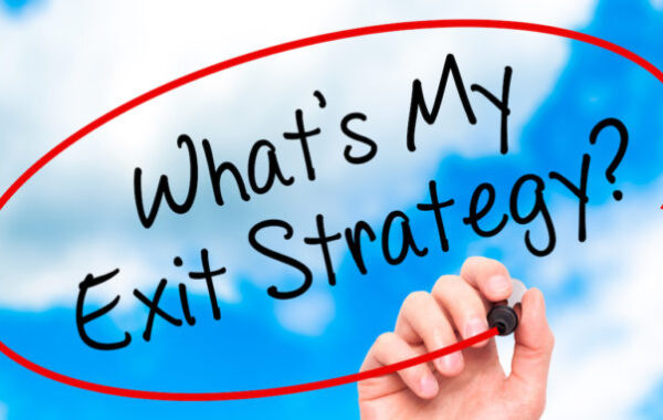 Hand circling the handwritten question 'What's My Exit Strategy?' on a glass board