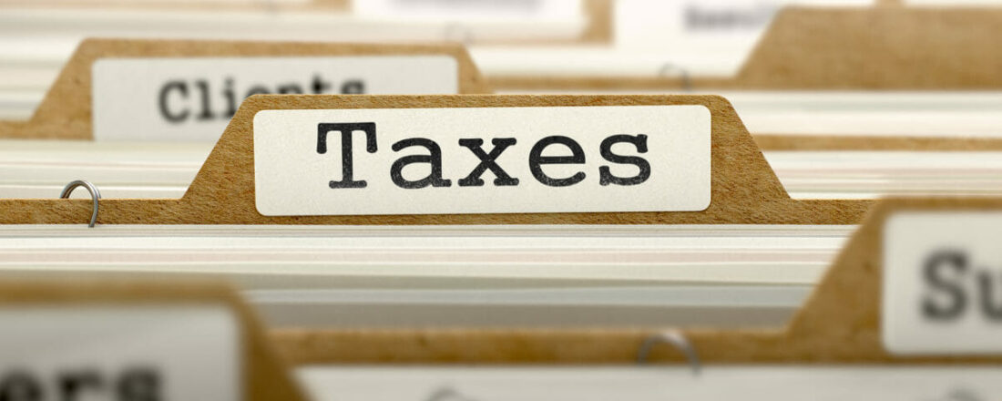 File folder labeled 'Taxes' among client files, representing tax planning for a business sale