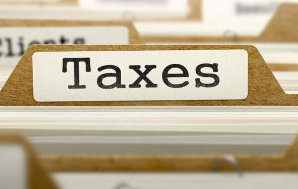 File folder labeled 'Taxes' among client files, representing tax planning for a business sale