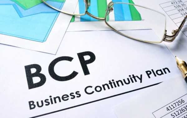 Business Continuity Plan (BCP) document with charts and reading glasses on a desk