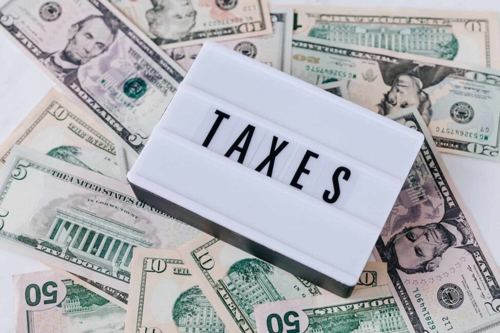 Stack of U.S. dollar bills with a lightbox sign reading 'Taxes,' symbolizing business tax planning